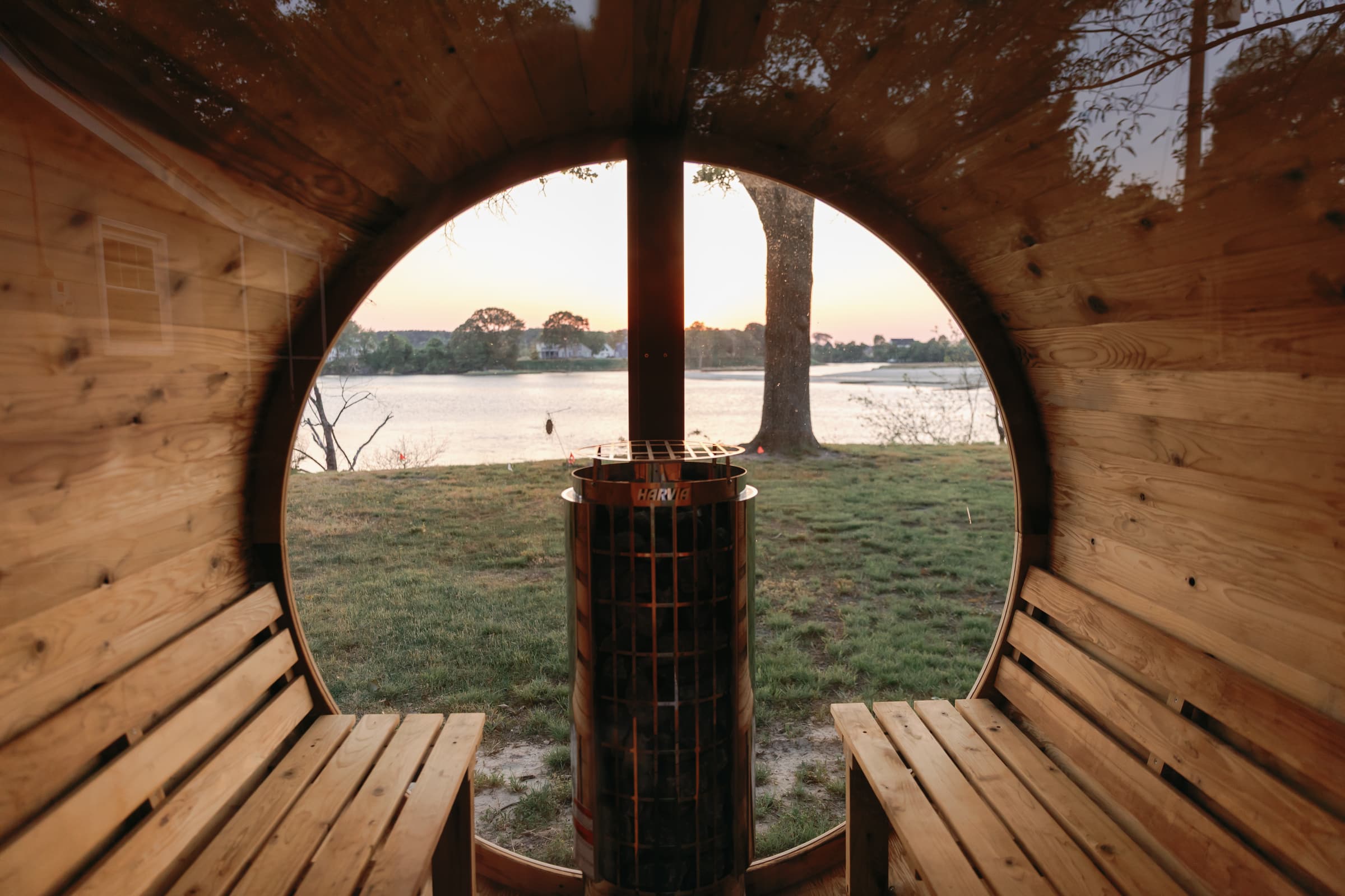 Inside the cedar barrel sauna at Captain's Cottage, looking out the round window across Hull Creek at sunset.