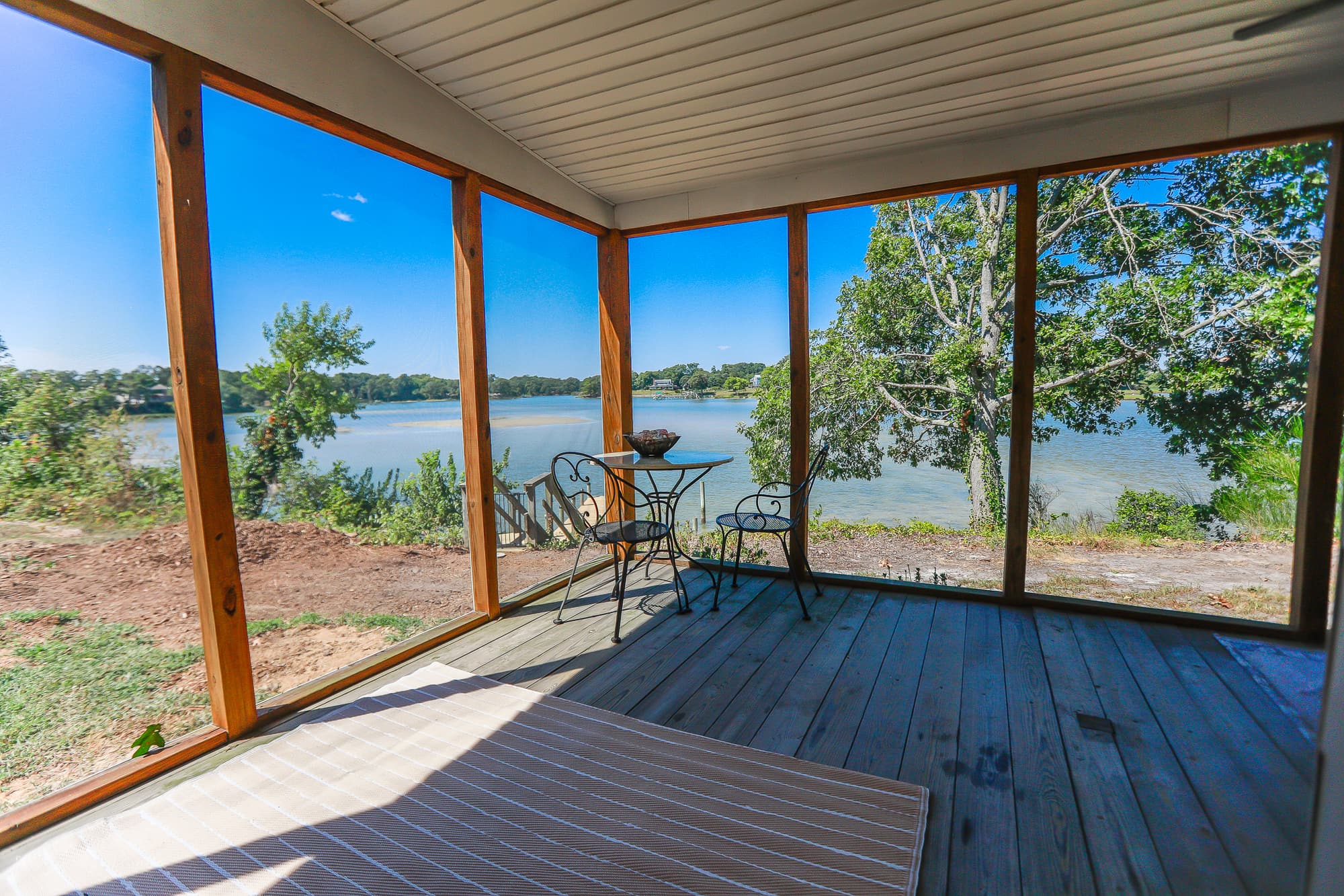 View from the screened porch at Captain's Cottage looking out across Hull Creek — cedar framing, the dock just below.