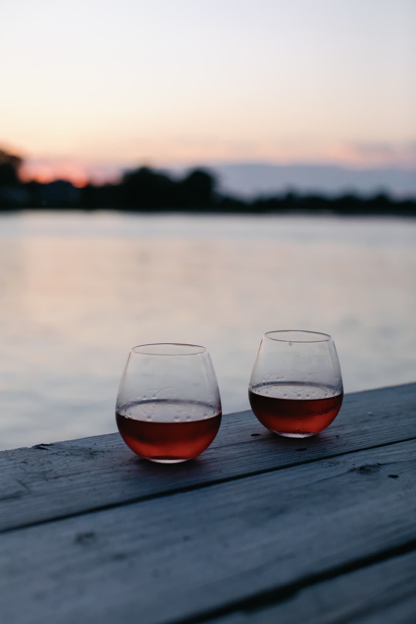 Two glasses of rosé on the dock at sunset over Hull Creek.